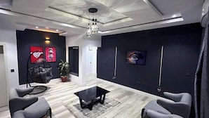 A modern living room with a black sofa set, a glass coffee table, and a hanging light fixture. - 99 Mozilla Apartments (Abuja)
