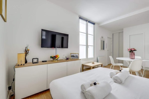 A hotel room with a bed, a TV, a desk, and a chair.