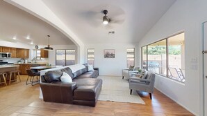 A spacious living area with a brown leather sofa, a grey armchair, and a dining table.