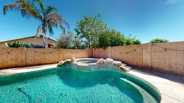 A swimming pool with a curved design, surrounded by a brick wall and a palm tree.