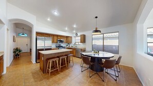 A modern kitchen with wooden cabinets, stainless steel appliances, and a central island with bar stools.