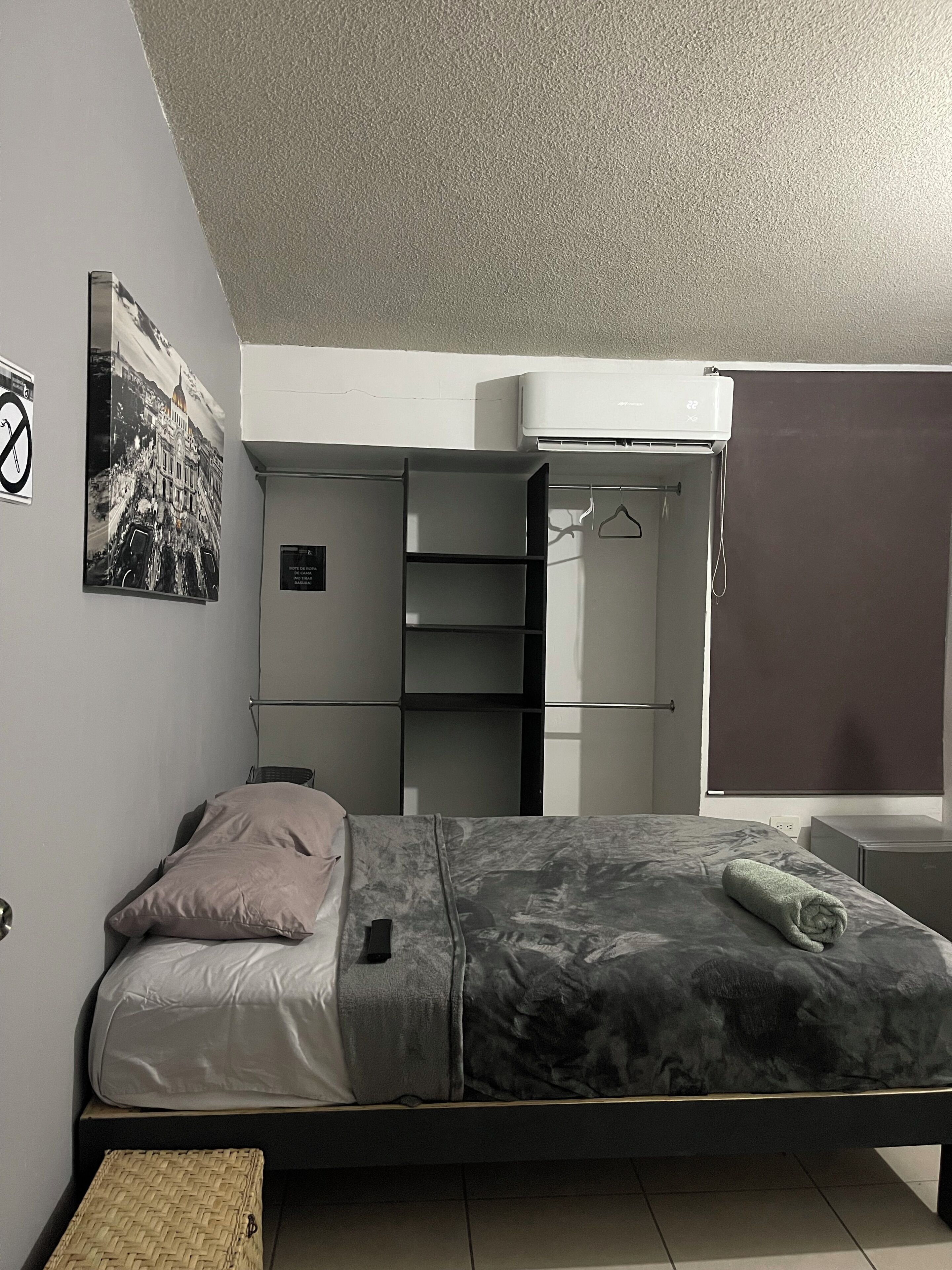 Ein Schlafzimmer mit einem Bett, einem Kleiderschrank, einer Kleiderstange und einem Bild an der Wand.