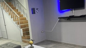 A modern living room with a staircase, a flat-screen TV mounted on a wall, and a coffee table with a globe on it. - House with Jacuzzi (La Paz)