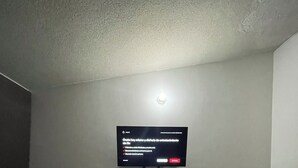 A hotel room with a bed, a TV mounted on the wall, a small table, and a chair. - House with Jacuzzi (La Paz)
