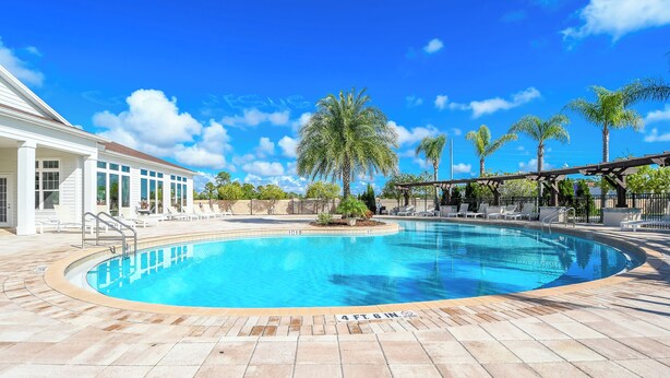 A clear blue swimming pool with a 4 ft. 6 in. depth marker, surrounded by a tiled deck and palm trees.