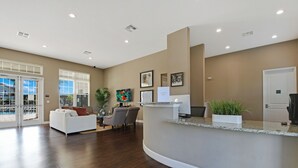 A reception area with a curved counter, seating with a white couch and chairs, framed pictures on the wall, and a door to the right.