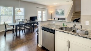 A modern kitchen with granite countertops, a dishwasher, and a dining area with a table and chairs.