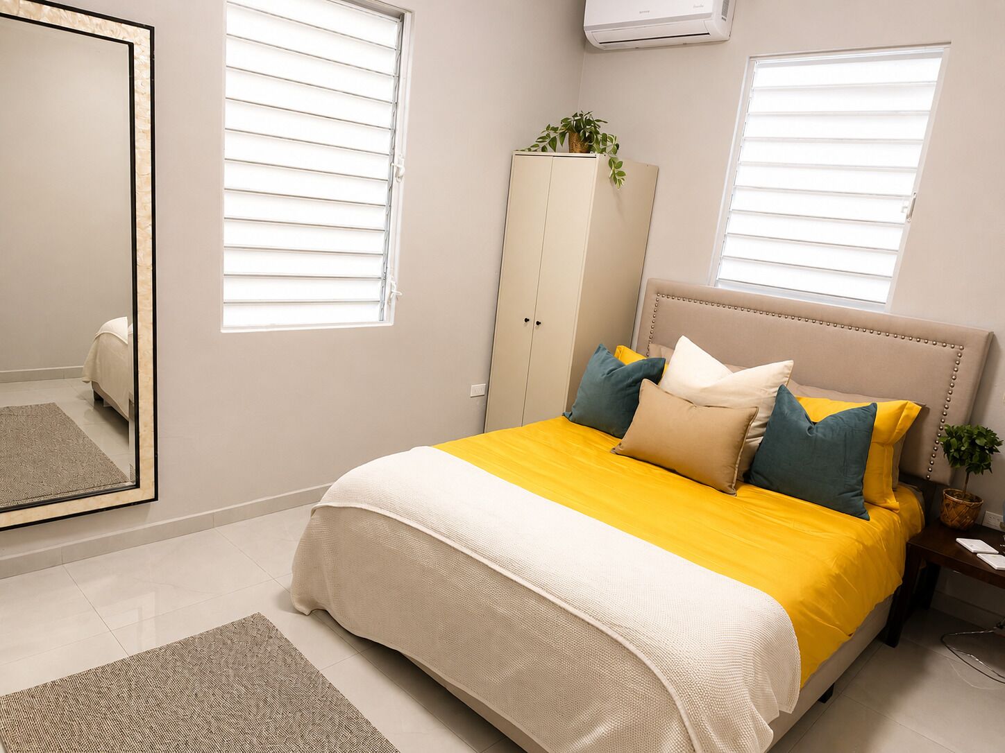 A bedroom with a bed, a wardrobe, a mirror, and a window.