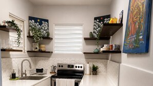 Une petite cuisine équipée d’une cuisinière, d’un évier et d’une poubelle.