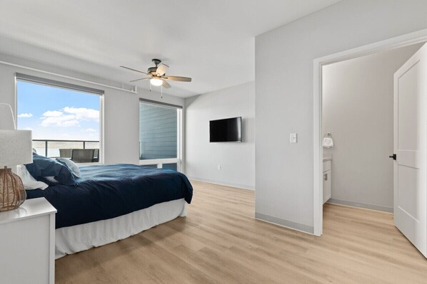 A bedroom with a bed, a ceiling fan, a TV, and a window with blinds.