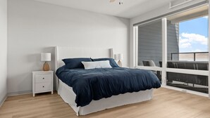 Un dormitorio con cama, mesitas de noche y un amplio ventanal con vistas.
