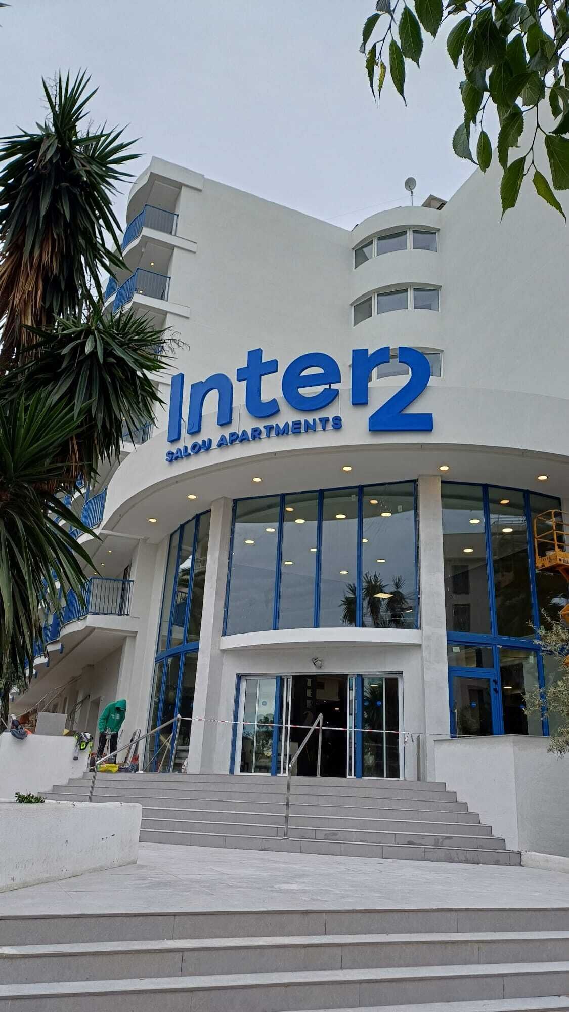 A building with a sign reading 'Inter2 SALON APARTMENTS' with a curved entrance and a staircase leading up to the entrance.