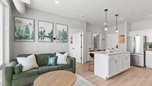 A modern kitchen with white cabinets, a stainless steel refrigerator, and a central island. - Condo with stunning views of Lake Pepin Unit 104 (Lake City)