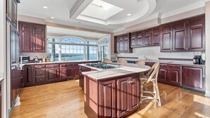 Uma cozinha espaçosa com armários de madeira escura, uma ilha central e uma janela grande que proporciona iluminação natural.
