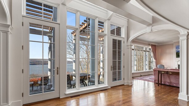 Um quarto amplo com grandes janelas, piso de madeira e vista para o exterior.