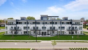 A modern hotel with a symmetrical facade, multiple balconies, and a central entrance.