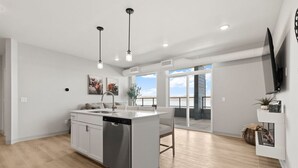 Una cocina moderna con una isla central, iluminación colgante y un amplio ventanal con vistas al exterior.