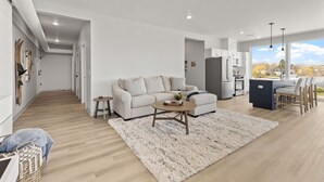 Ein modernes Wohnzimmer mit Sofa, Couchtisch und Blick zur Küche.