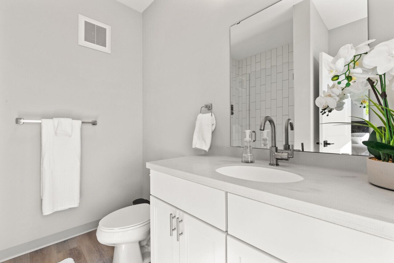 Een moderne badkamer met een wit wastafel, spiegel en toilet.