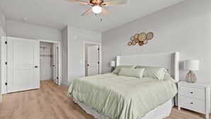 Una camera da letto con un letto, comodini, una ventola a soffitto e un punto luce a parete.