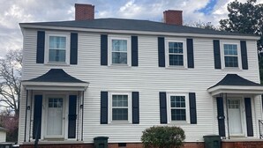 A two-story white house with black shutters, brick foundation, and a small front porch. - Charming 2-bedroom townhome in quaint Hamlet with WiFi, AC (Hamlet)