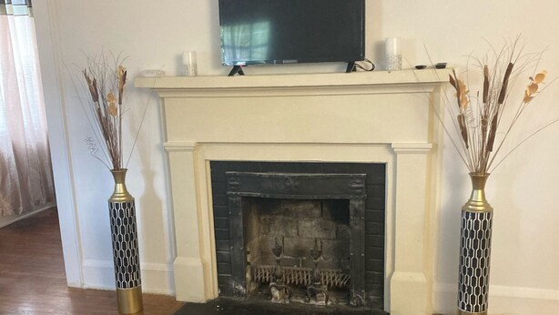 A living room with a fireplace, a television mounted above it, and two decorative vases on either side. - Charming 2-bedroom townhome in quaint Hamlet with WiFi, AC (Hamlet)