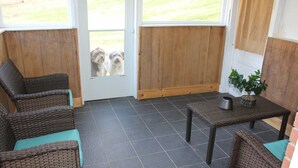 A covered patio area with wicker furniture, a small table with a plant, and a door leading outside. - Charming & Secluded Farm House (Somerset)