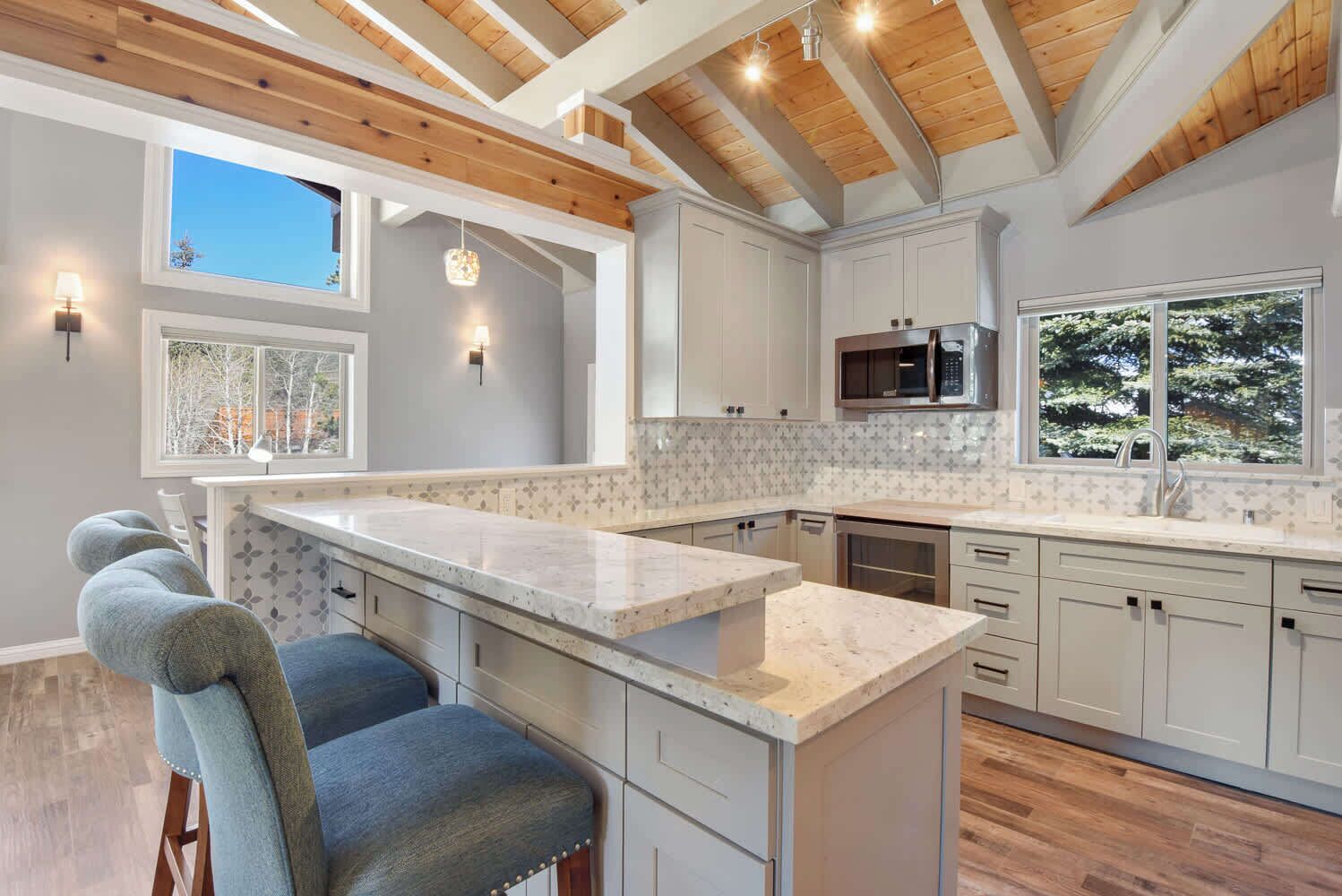 A modern kitchen with white cabinets, a marble countertop, and wooden beams on the ceiling.