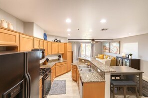 A modern kitchen with granite countertops, wooden cabinets, a built-in stove, and a dining area with a bench. - 2 Private Homes,  6BR With New Pool & 2 Spas, Lake Views and Boat Parking (Lake Havasu City)