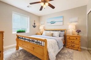 A bedroom with a wooden bed, two bedside tables with lamps, a ceiling fan, a window with blinds, and a wall-mounted anchor decoration. - 2 Private Homes,  6BR With New Pool & 2 Spas, Lake Views and Boat Parking (Lake Havasu City)
