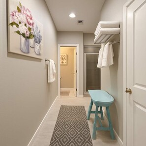 A hallway with a patterned rug, a blue stool, and a painting of flowers on the wall. - 2 Private Homes,  6BR With New Pool & 2 Spas, Lake Views and Boat Parking (Lake Havasu City)