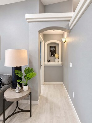 Un couloir avec une lampe, une plante en pot et un panneau fixé au mur.