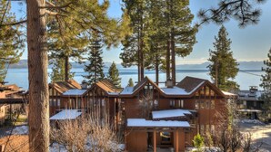Un hotel de estilo cabaña con varias construcciones de madera, suelo cubierto de nieve y vista al lago.