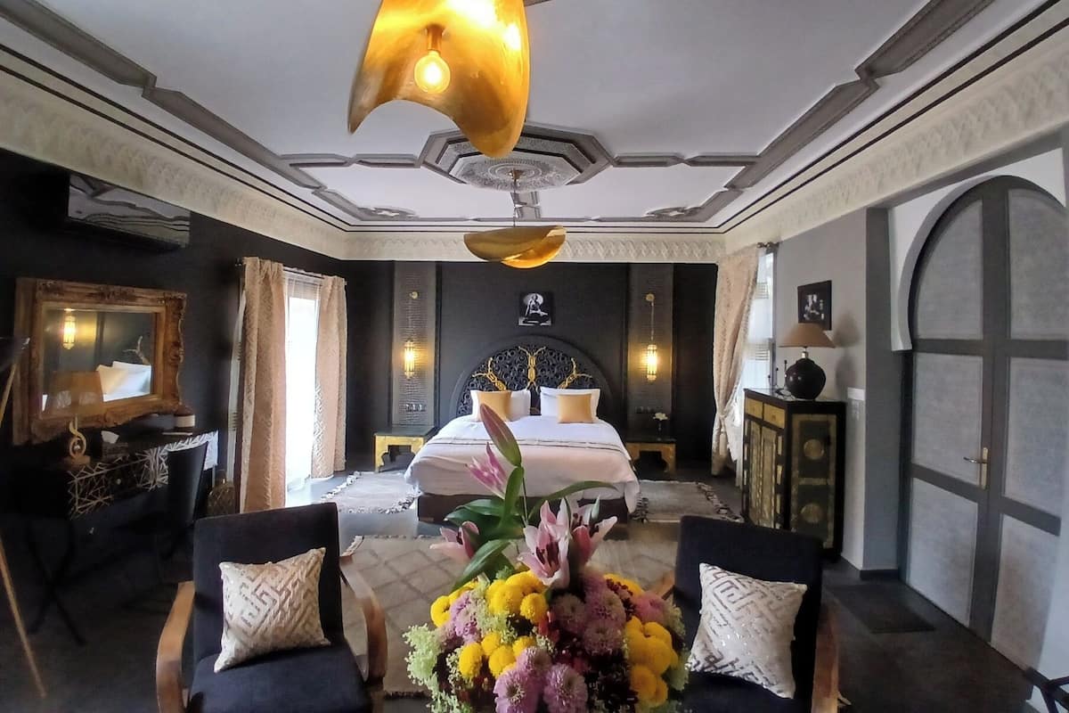 Un dormitorio lujoso con una cama grande, un candelabro y un arreglo floral.