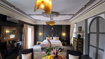 Een luxueuze slaapkamer met een groot bed, een kroonluchter en een bloemstuk.