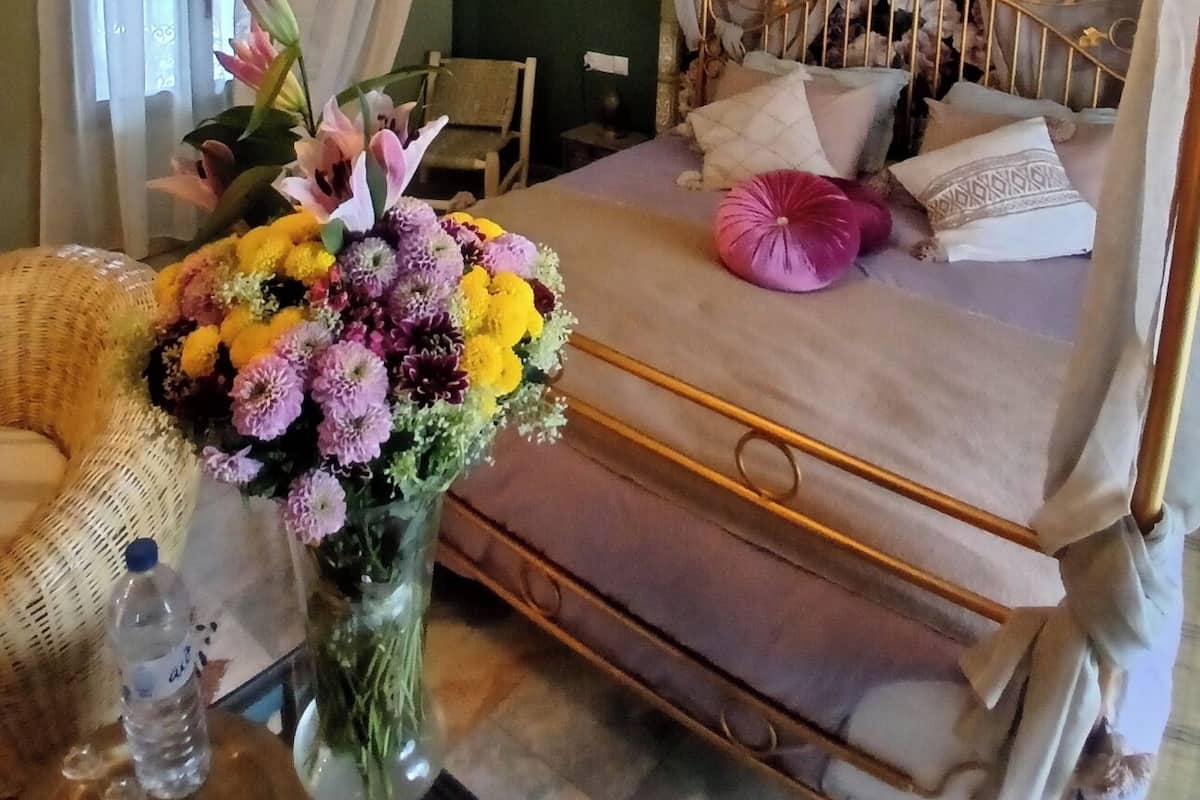 Una cama con dosel, un jarrón de flores y un adorno en la pared.