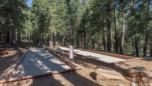 A forested area with a concrete path, benches, and a signpost. - A Golden Getaway | Pool, Hot Tub, Tennis, & More (Truckee)