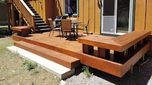 A wooden deck with outdoor seating and a staircase leading to a deck area.