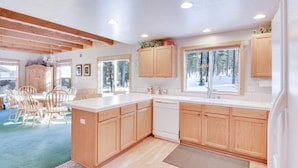 A modern kitchen with wooden cabinets, a central island, and a dining area with chairs.