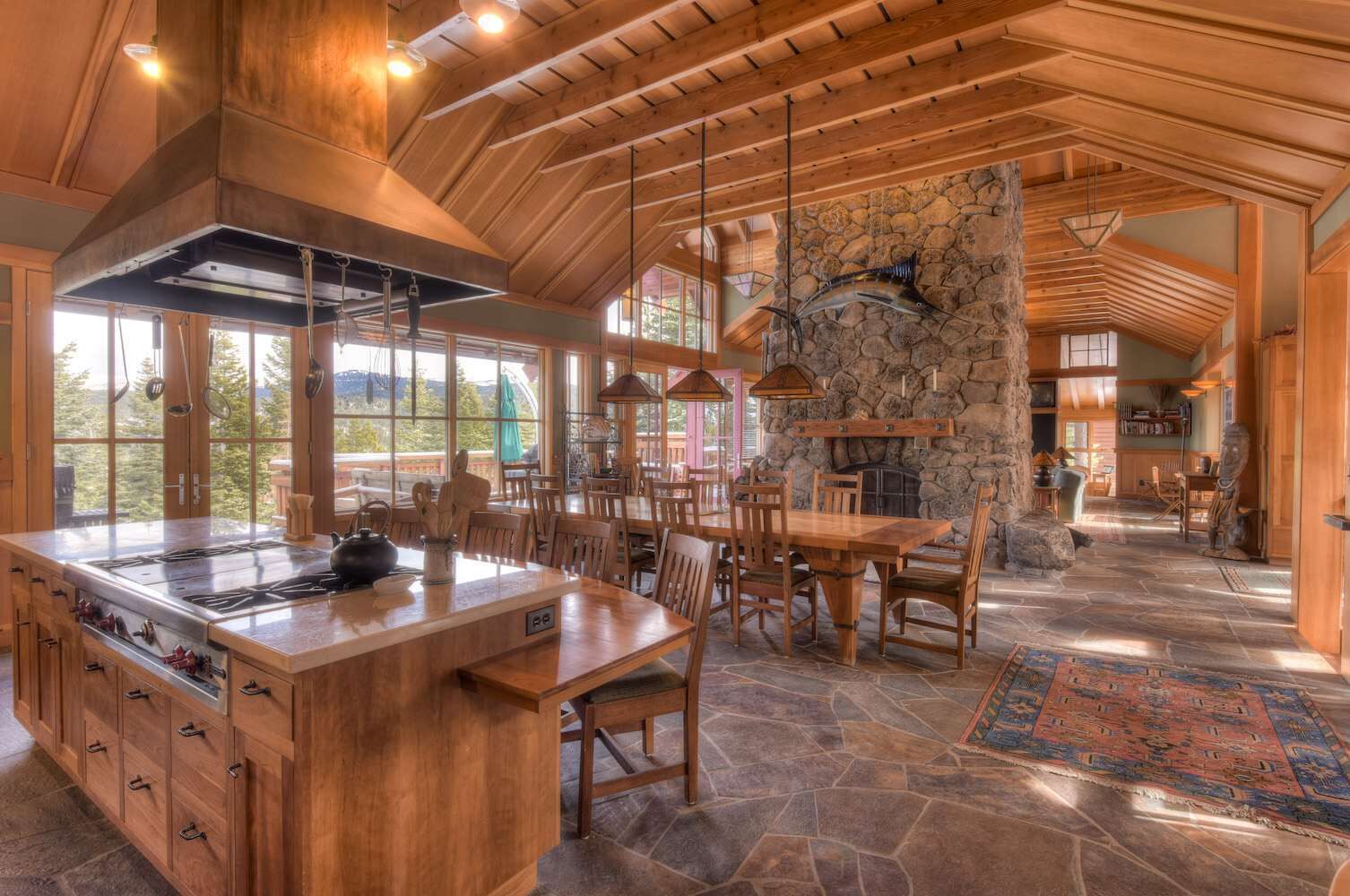 A spacious kitchen with a large island, stone walls, and wooden beams.