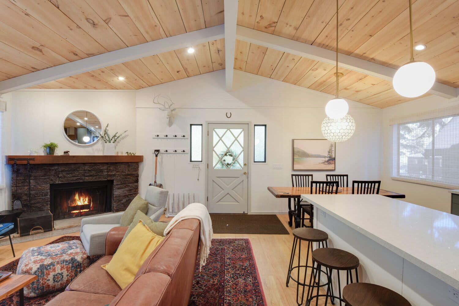 A spacious living room with a fireplace, a dining area with a high wooden ceiling, and a kitchen with a large island.
