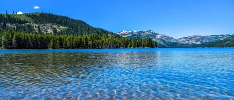 A clear lake with visible lakebed and surrounding forested hills.