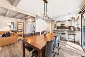 Una cocina moderna con electrodomésticos de acero inoxidable, una mesa de comedor de madera y taburetes de bar.