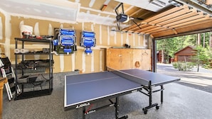 Une table de ping-pong dans une pièce dotée d’un plafond en bois et offrant une vue sur une forêt.
