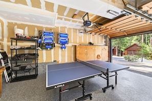 Une table de ping-pong dans une pièce dotée d’un plafond en bois et offrant une vue sur une forêt.