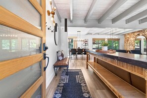 A modern kitchen with a wooden bench, a bar area, and a view of the outdoors.
