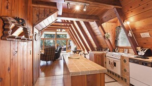 A rustic kitchen with wooden beams, a stone countertop, and a view of the outdoors.