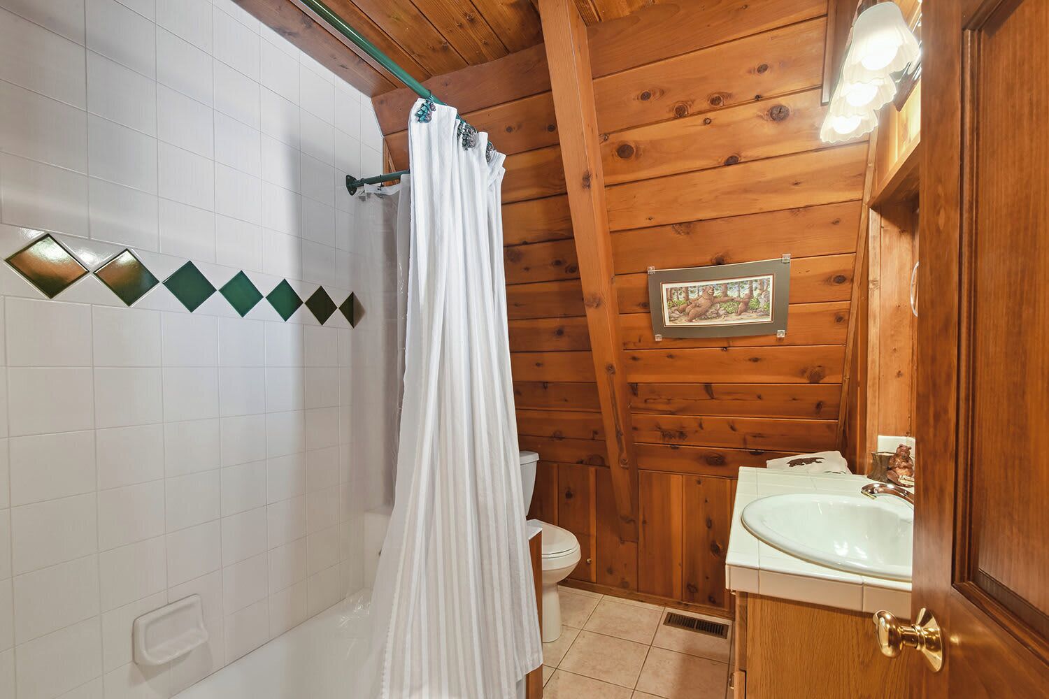 Une salle de bain rustique, aménagée dans une cabane en bois, avec un rideau de douche, des toilettes et un lavabo.