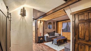Un soggiorno accogliente con camino, travi in legno e un'ampia porta in legno.