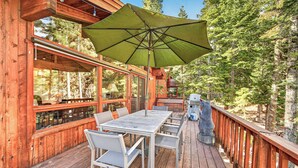 Une terrasse en bois avec une table et des chaises, un parasol et un barbecue.